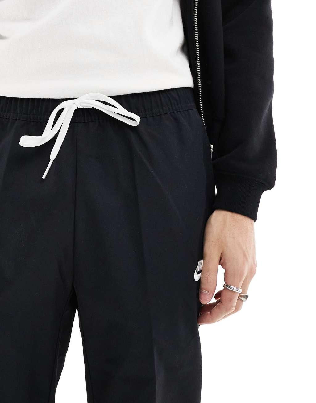 Nike Club woven tapered pants in black Product Image